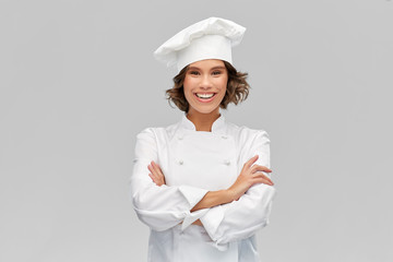 cooking, culinary and people concept - happy smiling female chef in toque with crossed arms over grey background - obrazy, fototapety, plakaty