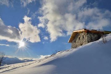 traditional alpine chalet at the top of snowy mountain under sunrise in the  sky