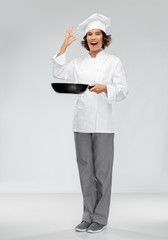 cooking, culinary and people concept - happy smiling female chef in toque with frying pan showing ok hand sign over grey background