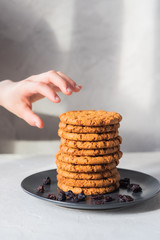 Children's hand stretching in a stack of freshly baked homemade cookies. Traditional fresh baked biscuits. The concept of fast food, cooking, baking and food.
