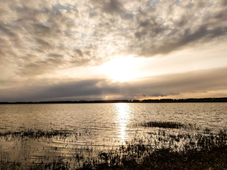 sunset in the clouds over a river with reeds