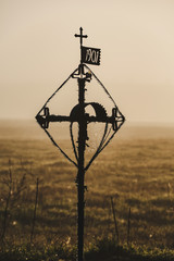 Obraz premium Cross by the road. Old chapel. Spider web and sun rise.