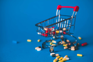 Red basket with a bunch of pills on a blue background