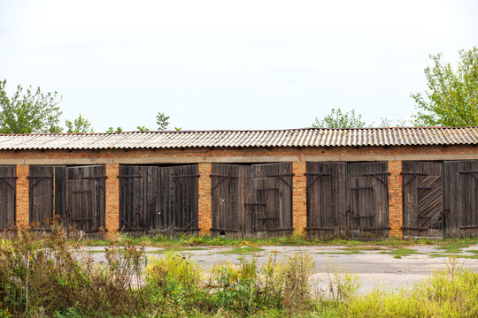 Old cowshed. Large wooden gate and dried wood. Old brick building