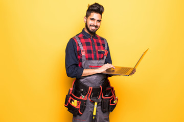 Indian beard repairman using laptop against yellow background