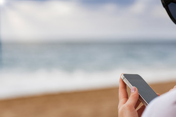 Young woman lying with smart phone on a beach. Relaxation concept