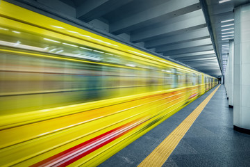 Subway train arriving to metro station. Motion blur of high speed train in subway. Yellow metro train.