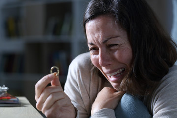Sad wife crying looking at wedding ring in the night at home