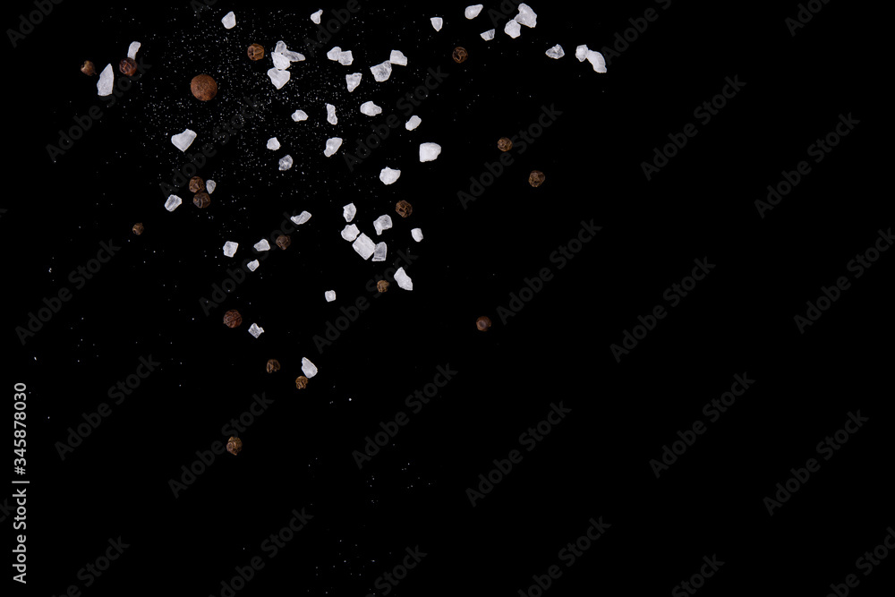 Wall mural levitating salt crystals and black pepper spice on black. copy space