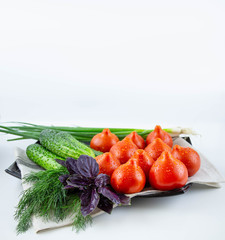 Tomatoes with cucumbers and basil and dill on a plate. 