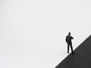 A miniature businessman having one foot in black background. The dark side concept image.