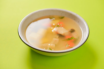 Delicious stew soup with meat and vegetables served in a white bowl over bright green background. Healthy diet.