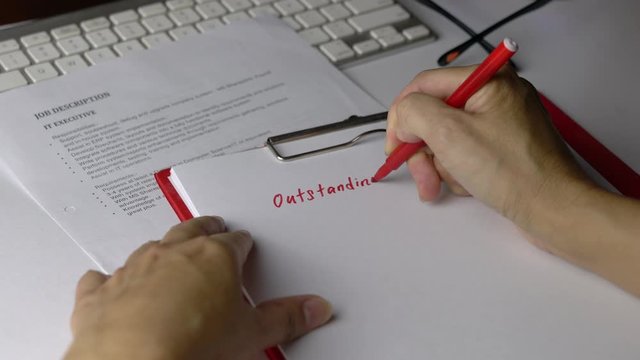Hiring Manager writing down outstanding vacancies on a piece of paper with Job Description of positions on the office table. Employment concept.