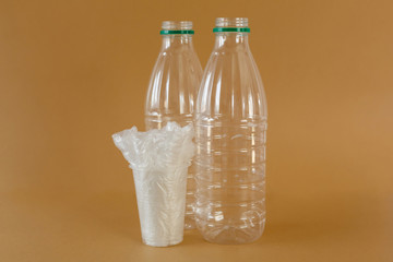 plastic bottles and plastic bags in a glass on a brown background