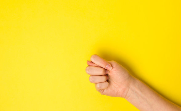 Close-up fig sign. Woman Hand Gesture on yellow background. Flat lay. Copy space