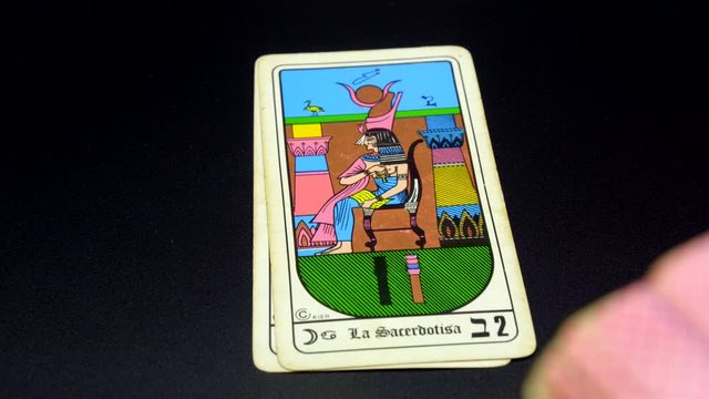 A hand lays out, Vintage Egyptian Tarot, full major arcana set on black tablecloth. Tokyo, Japan. March 2020. Camera fixed, close-up, point of view shot.