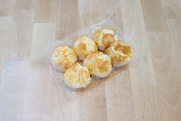 Choux cream in plastic box on wood table