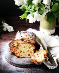 Curd cake with raisins on a cutting board on a dark background with lilac flowers