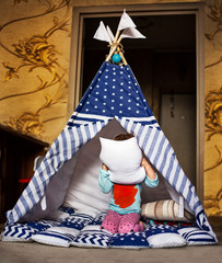 little girl play in a teepee in her children's room. Entertainment for kids at home. Lesson for children during quarantine. Girl playing with pillow challenge in tent wigwam play room.  © Iryna