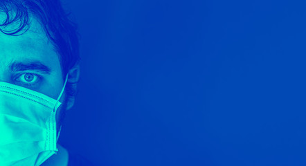 Half of the face of a person wearing a protective mask against the coronavirus Covid-19 - Surgical type anti-splash mask - Duotone on a blue background