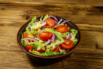 Healthy salad with savoy cabbage, cherry tomato, red onion and olive oil on wooden table