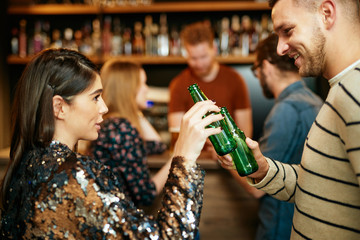 Two best friends standing at pub and toasting with craft beer.