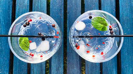 Gin tonic cocktail drink in glass with ice garnish and straw top view