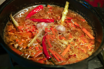 Preparing pilaf in a cauldron, process of cooking. Bright red chilly pepper, carrot, garlic merged...