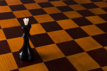 Closeup of black chess queen on the empty wooden chess board.Free space.Concept of executive leader