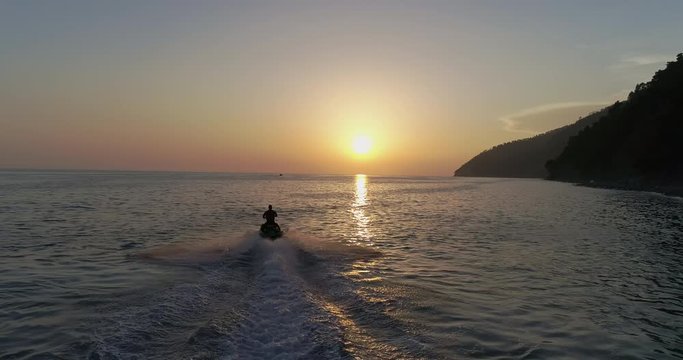 AERIAL TOP: Jet ski is sailing on the sea under sunset. sport riding a personal watercraft. stunt riding on jet ski. riding a new model of water bike on the sea. Sports and holidays