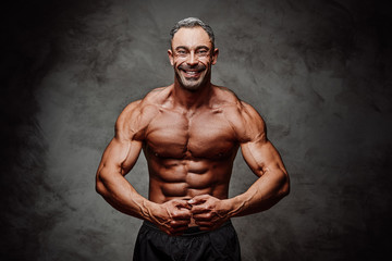 Handsome adult sportsman wearing sportswear posing for a camera while showing his chest muscles