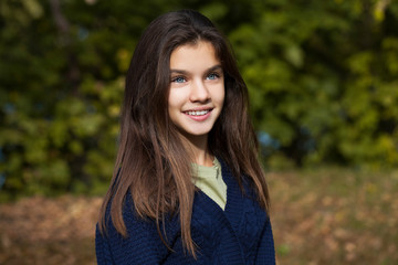 Fototapeta premium Pretty brunette little girl posing in autumn park background