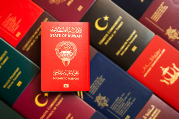 Kuwait diplomatic passport on blurred background of various documents of the world.