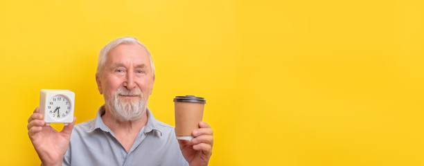 Senior man is holds clock coffe mug banner copy space. Seniors morning.