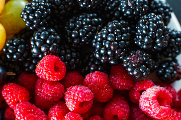 Close-up of raspberry and black mulberry berries split frame. Summer vitamins, sweet berries.