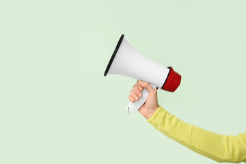 Female hand with megaphone on color background