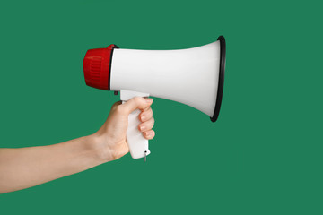 Hand of young woman with megaphone on color background