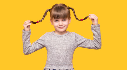 Portrait of candid dreamy child enjoy weekends holidays smile and touch her pigtails isolated on...