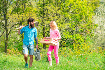 Fototapeta premium A pair of farms carries boxes with vegetables and greens along the field. Couple Gardener. Portrait of wife and husband while working in garden. Wife and husband spend time in the orchard. Earth day.