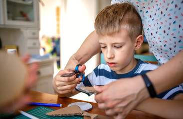 Mother helping son to cut cardboard, quarantine project