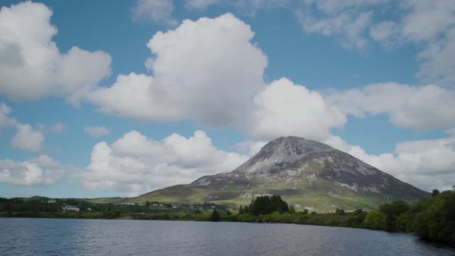 Wide of Mount Errigal, Donegal, Ireland.  Lake in foreground.  Moving white clouds in a blue sky.