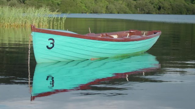 A wooden boat on a quiet Irish lake with reflections