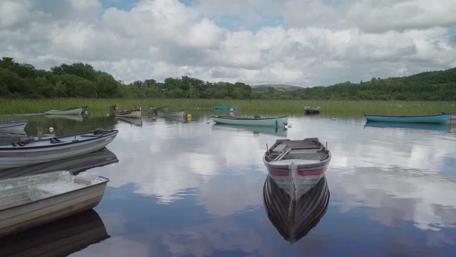 Wooden boats on still lake with cloud reflections