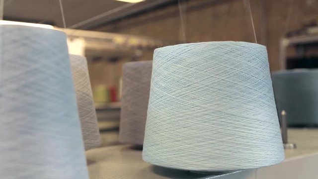 Close up shot of the thread bobbins on a weaving machine.