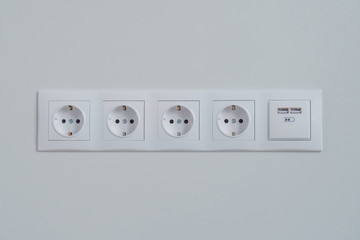 Group of empty, unplugged white electrical european outlet, socket with usb port located on gray wall - close up front view. Equipment, design, electricity, energy, technology concept