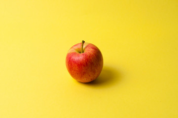 One red apple on a yellow background. The concept of ideas, weight loss and proper nutrition