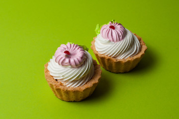Two delicious pastries with cream on a green background