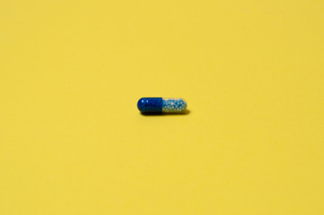 Blue pill on a yellow background, isolate, with place for text