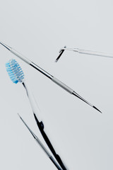 Dental instruments and toothbrush with blue bristles isolated on grey background