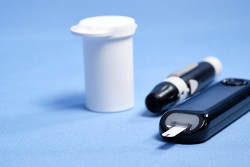 The glucometer with the test strip on a blue background. space for text. selective focus